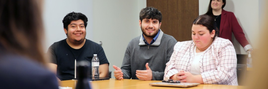 Three IU Indianapolis students sitting a boardroom table during a class workshop