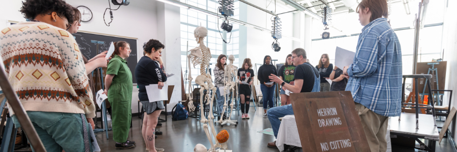Herron students surrounding a faux skeleton during a drawing workshop